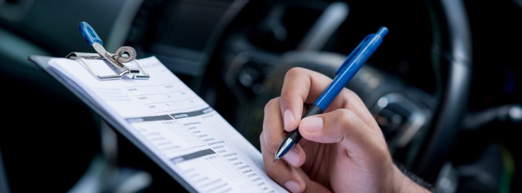 A car maintenance worker is checking a list of the car interior for a workshop customer.