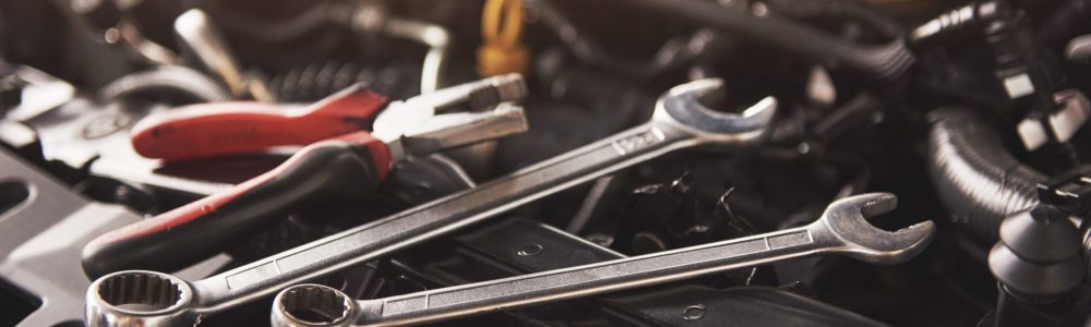 Mechanic hand checking and fixing a broken car in car service garage.